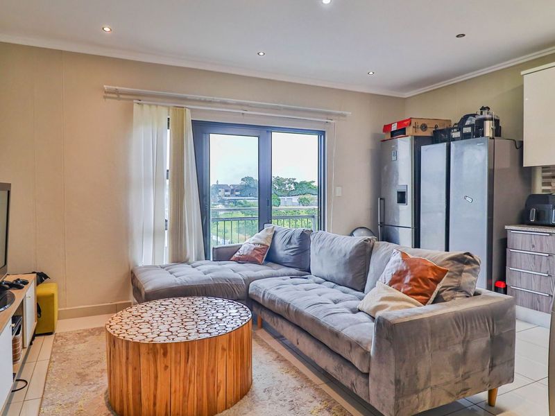 Open-plan living area featuring a modern kitchen with stone countertops and direct access to a balcony through sliding glass doors.