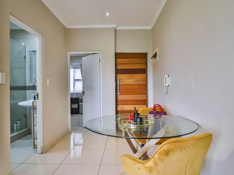 A bright hallway featuring tiled flooring, a solid timber entrance door, and an intercom system, providing access to adjacent rooms.