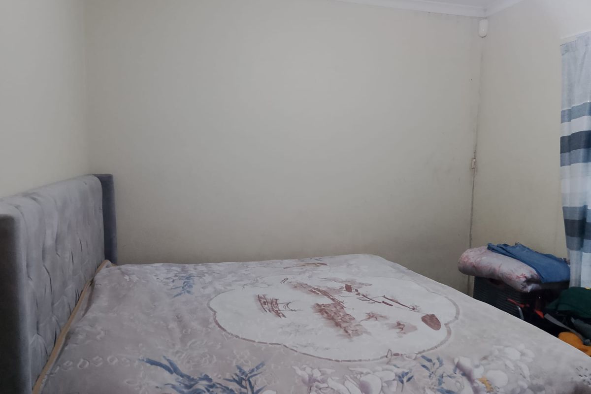 A bedroom featuring neutral walls with coving and a security sensor, requiring minor cosmetic updates to improve the overall finish.