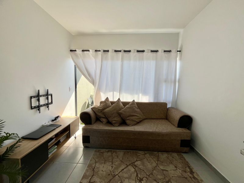 A compact living room featuring tiled flooring and a sliding glass door that provides access to an outdoor area.