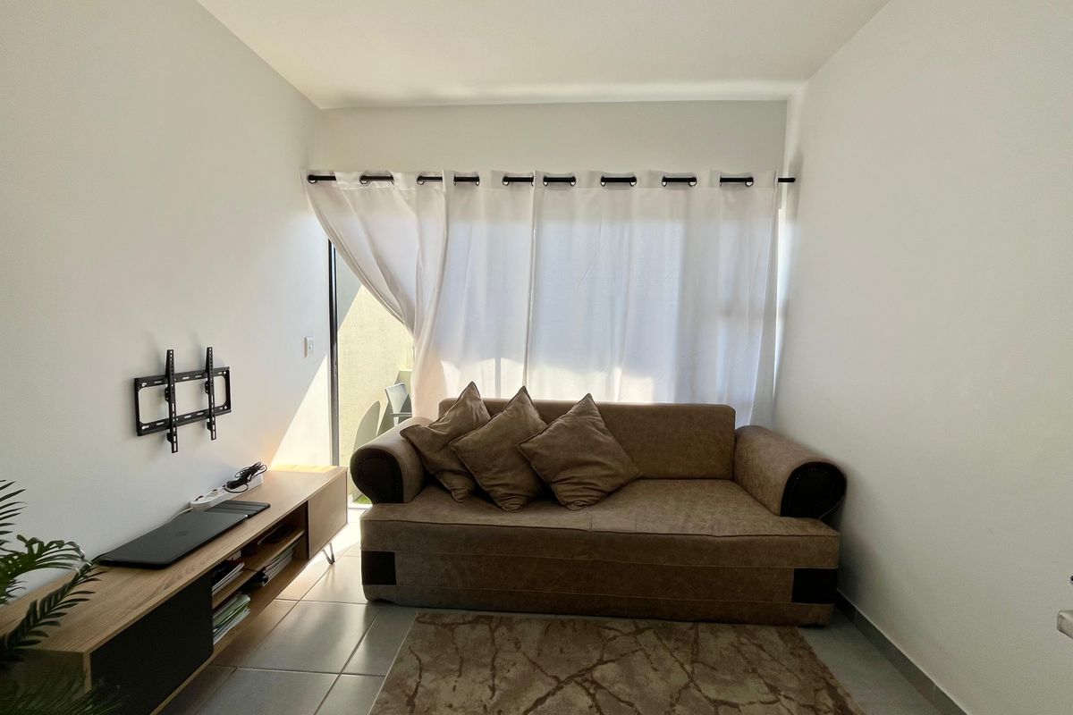 A compact living room featuring tiled flooring and a sliding glass door that provides access to an outdoor area.