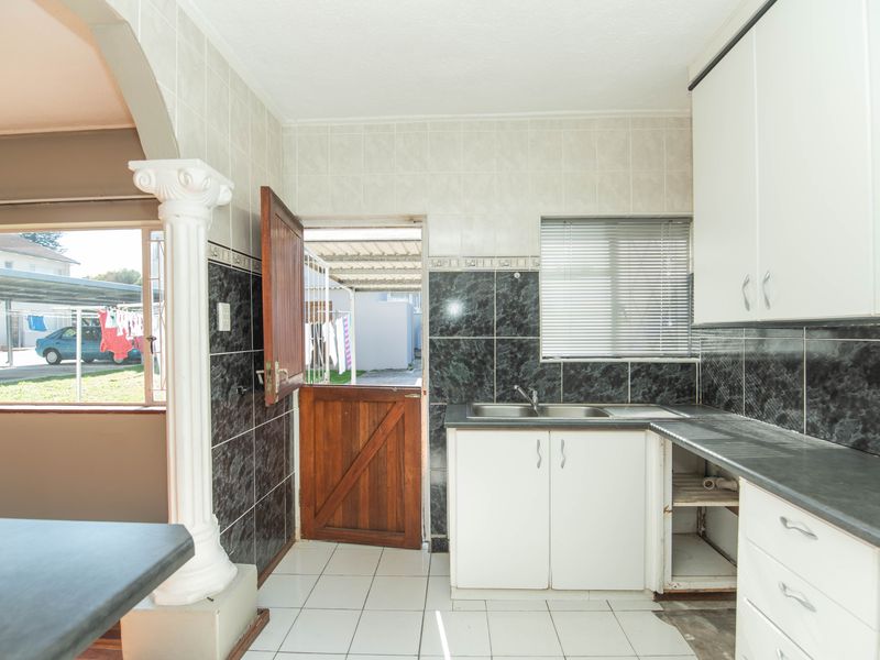 Kitchen featuring dark tiled backsplash, laminate countertops, stainless steel sink, and built-in cabinetry with direct access to the exterior via a stable door.