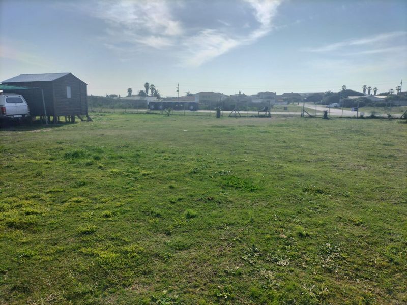 A large, open grassed plot featuring perimeter wire fencing and a small elevated wooden structure.
