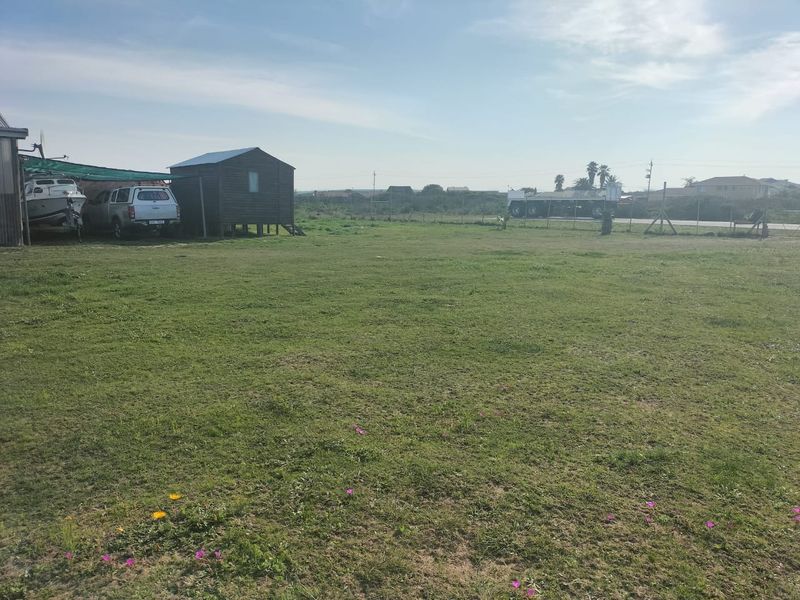 A large, open grassed garden area featuring a timber shed and perimeter wire fencing.