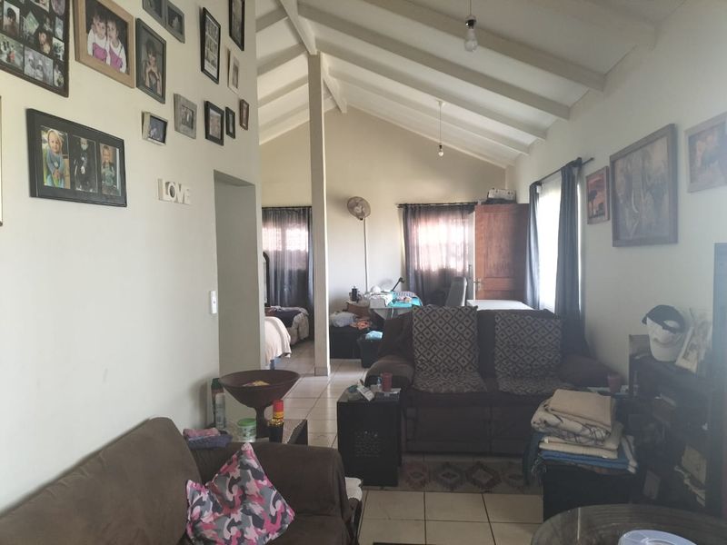 A living room featuring a high vaulted ceiling with exposed rafters and tiled flooring, offering a spacious feel with natural light.