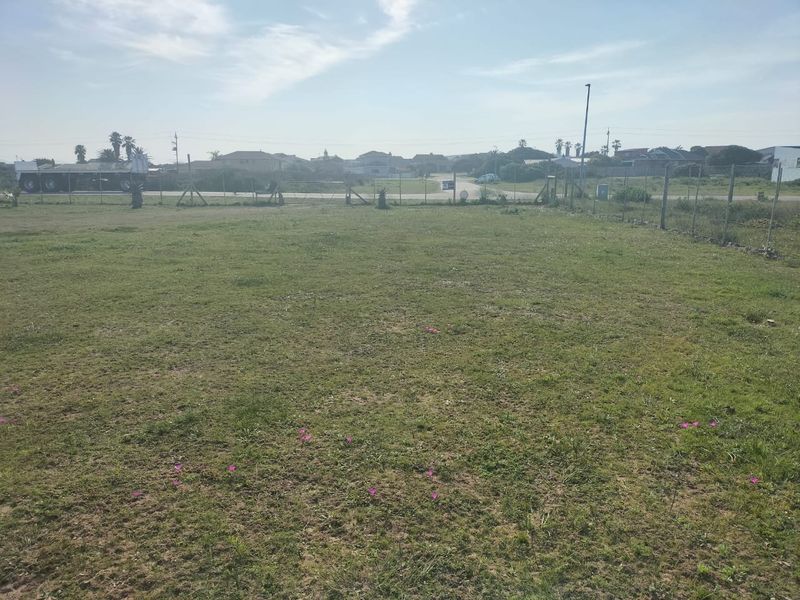 A large, open grass plot enclosed by wire mesh fencing, offering a clear view of the surrounding neighborhood.