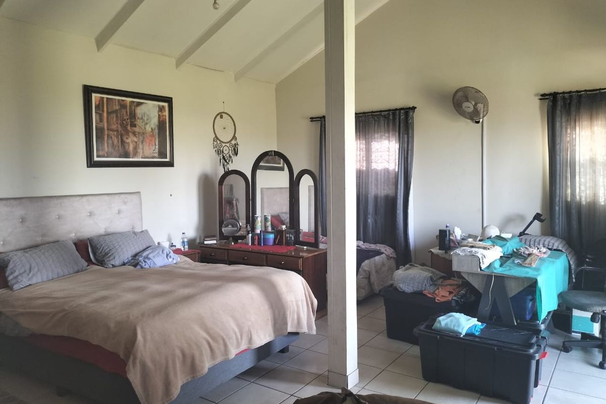 Spacious bedroom featuring a vaulted ceiling with exposed beams and tiled flooring, offering a functional layout with ample natural light.