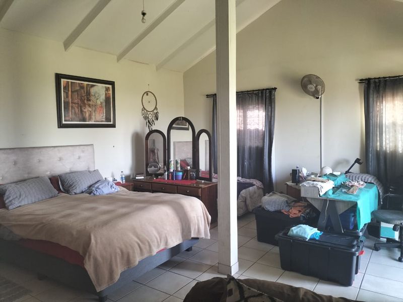 Spacious bedroom featuring a vaulted ceiling with exposed beams and tiled flooring, offering a functional layout with ample natural light.