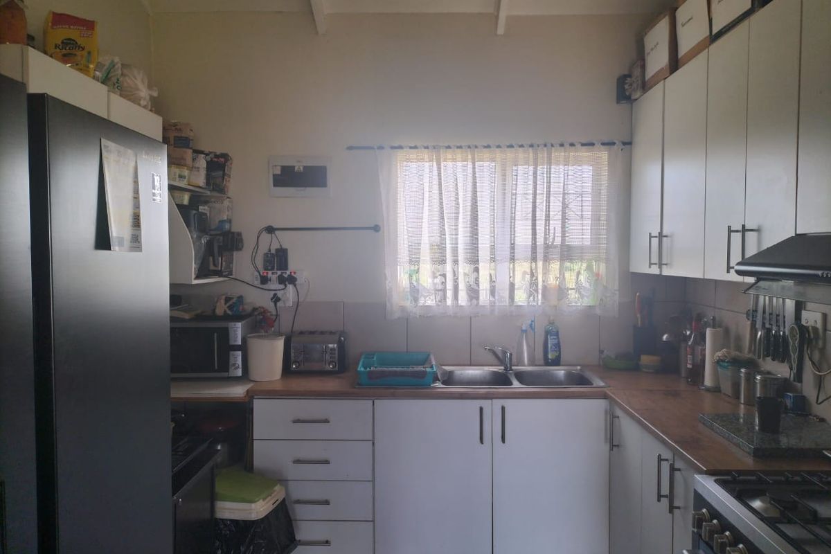 A functional kitchen featuring white cabinetry, laminate countertops, a double basin sink, and a built-in gas hob with an extractor fan.