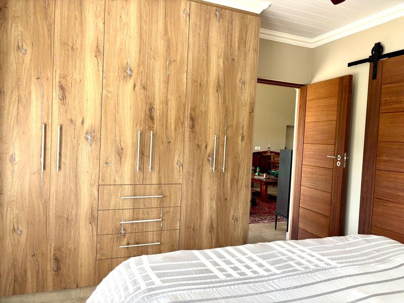 A well-maintained bedroom featuring extensive wood-grain built-in cupboards, a sliding barn door, and a classic tongue and groove ceiling.
