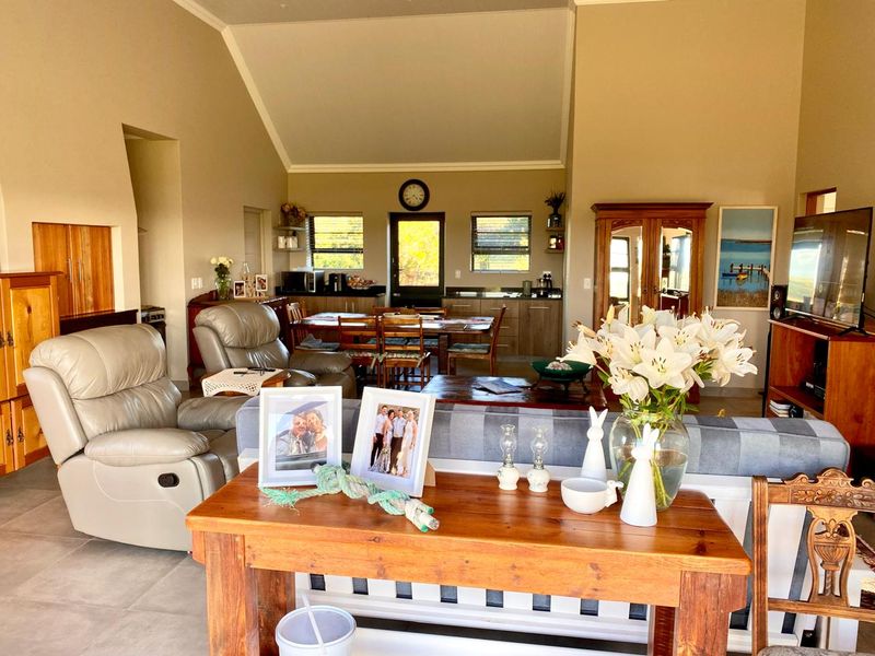 Spacious open-plan living and dining area featuring a high vaulted ceiling, tiled flooring, and an integrated kitchen space with built-in cabinetry.
