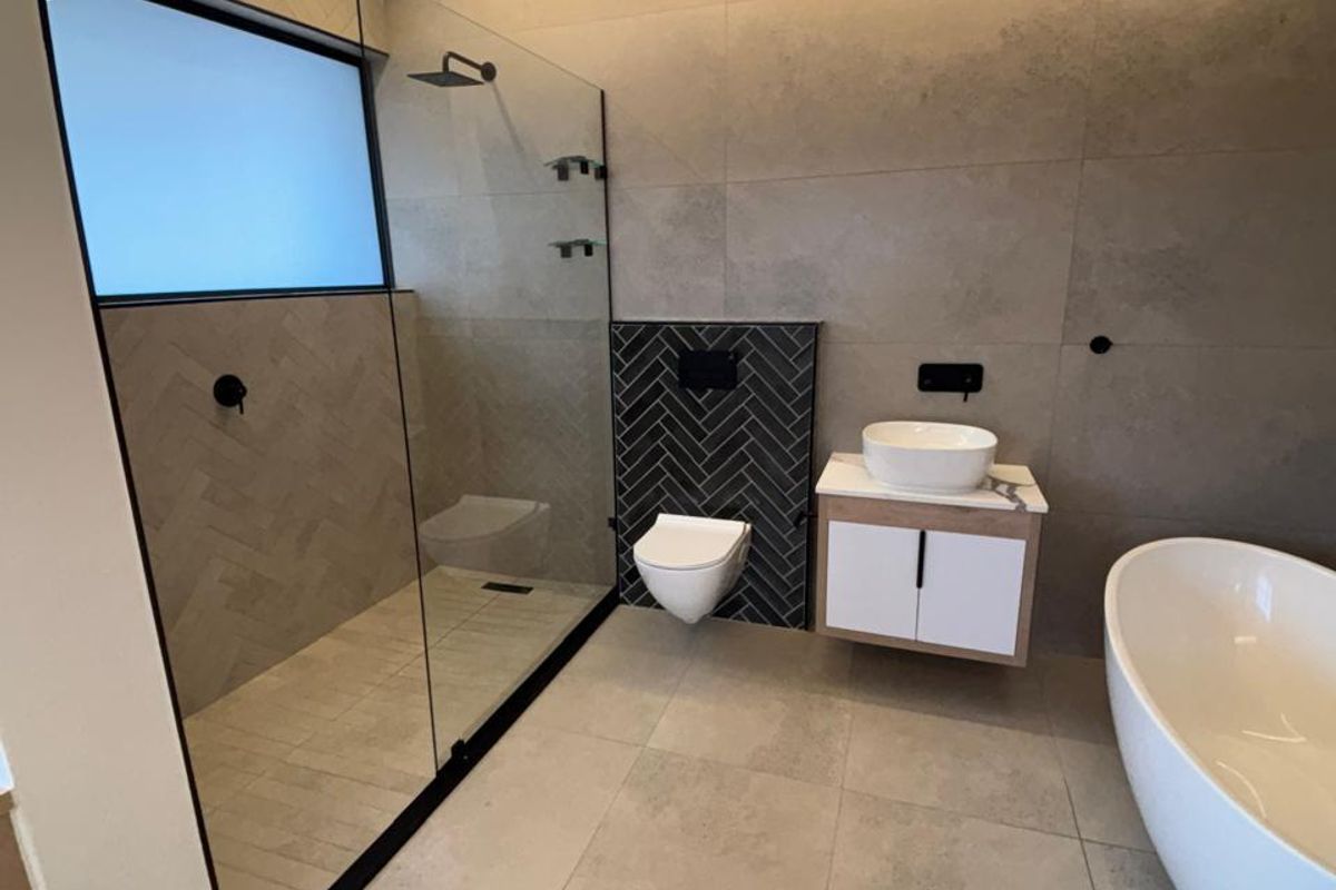 Modern, high-end bathroom featuring a walk-in shower, floating vanity, wall-mounted toilet, and a sleek freestanding bathtub with contemporary tiled finishes.