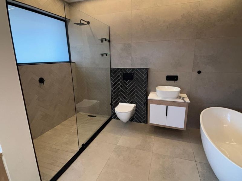 Modern, high-end bathroom featuring a walk-in shower, floating vanity, wall-mounted toilet, and a sleek freestanding bathtub with contemporary tiled finishes.