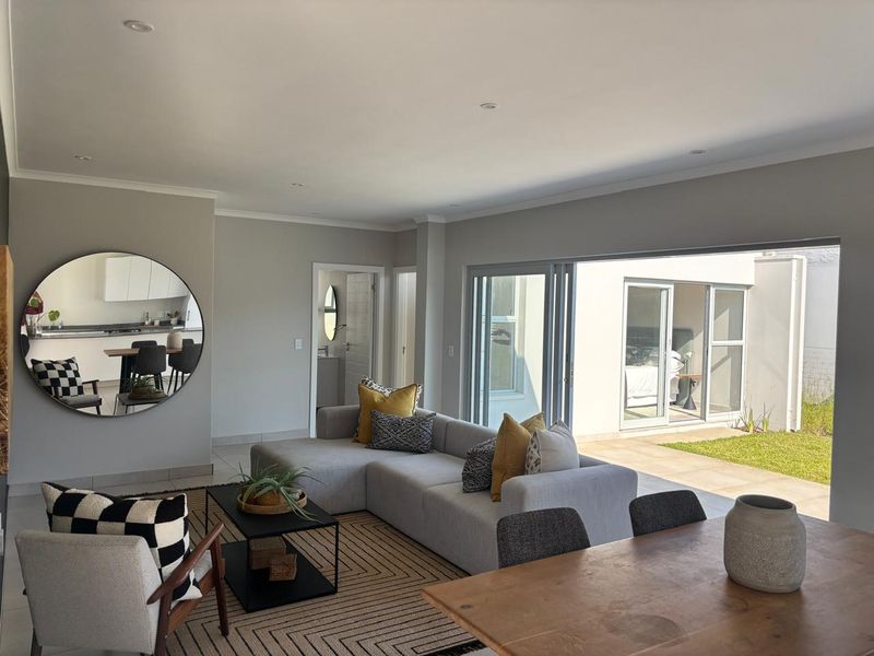 Spacious open-plan living area featuring modern tiled floors, recessed lighting, and large sliding glass doors that provide seamless access to the outdoor patio.