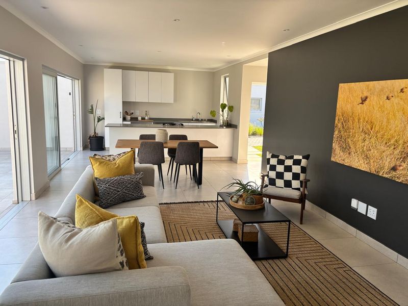 Spacious open-plan living and dining area featuring modern kitchen cabinetry, tiled floors, and large sliding glass doors leading to the outdoor space.