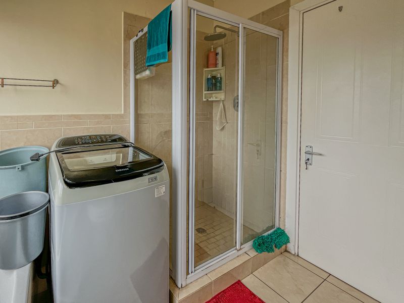 A functional bathroom featuring a tiled shower enclosure and tiled flooring, providing essential utility space within the apartment.