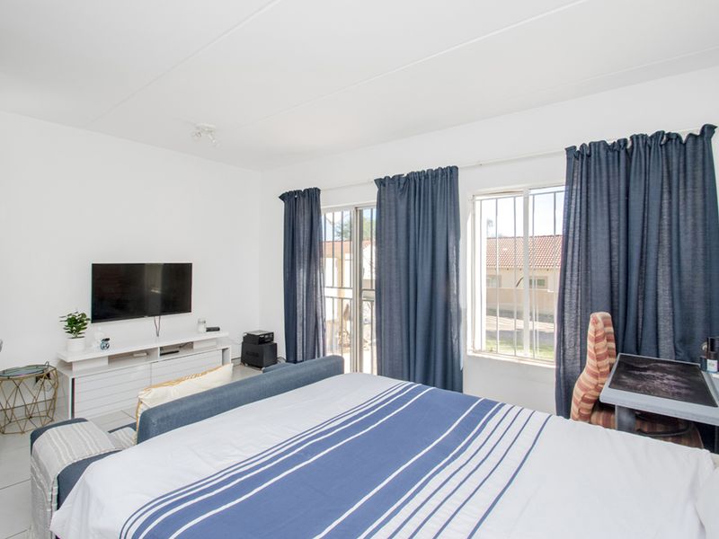 A bedroom featuring tiled flooring, security bars on the windows, and a sliding door providing access to the exterior.