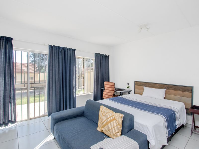A bedroom featuring tiled flooring and a sliding glass door with security bars, providing direct access to the exterior.