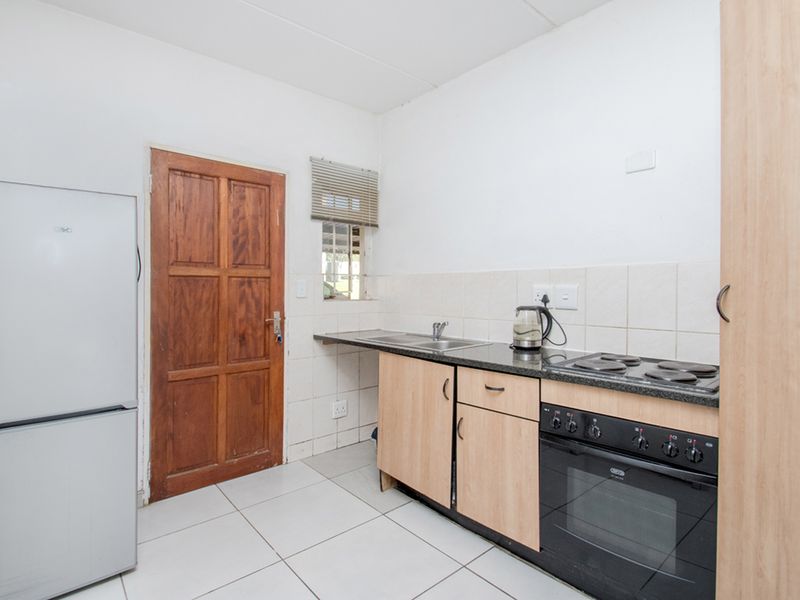 A functional kitchen featuring built-in cabinetry, granite countertops, a built-in oven with hob, and tiled flooring.