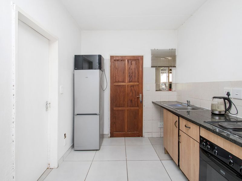 A functional kitchen featuring built-in cabinetry, granite countertops, a stainless steel sink, and a built-in oven with an electric hob.
