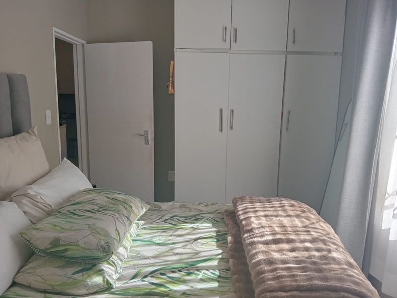A functional bedroom featuring built-in cupboards and neutral wall finishes, providing practical storage space.