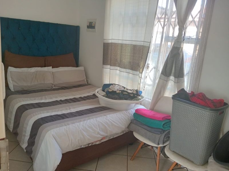A functional bedroom featuring tiled flooring and a window fitted with a security gate.