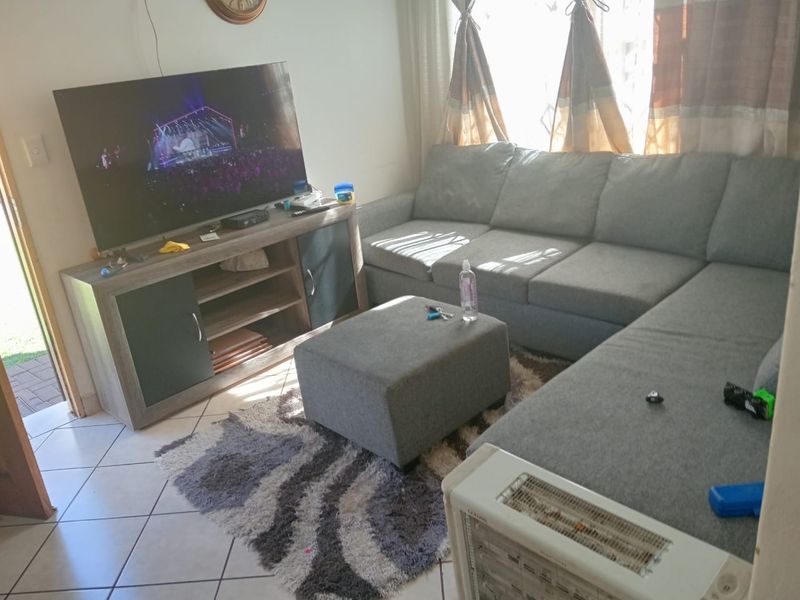 A comfortable living room featuring tiled flooring and direct access to the exterior via a sliding door.