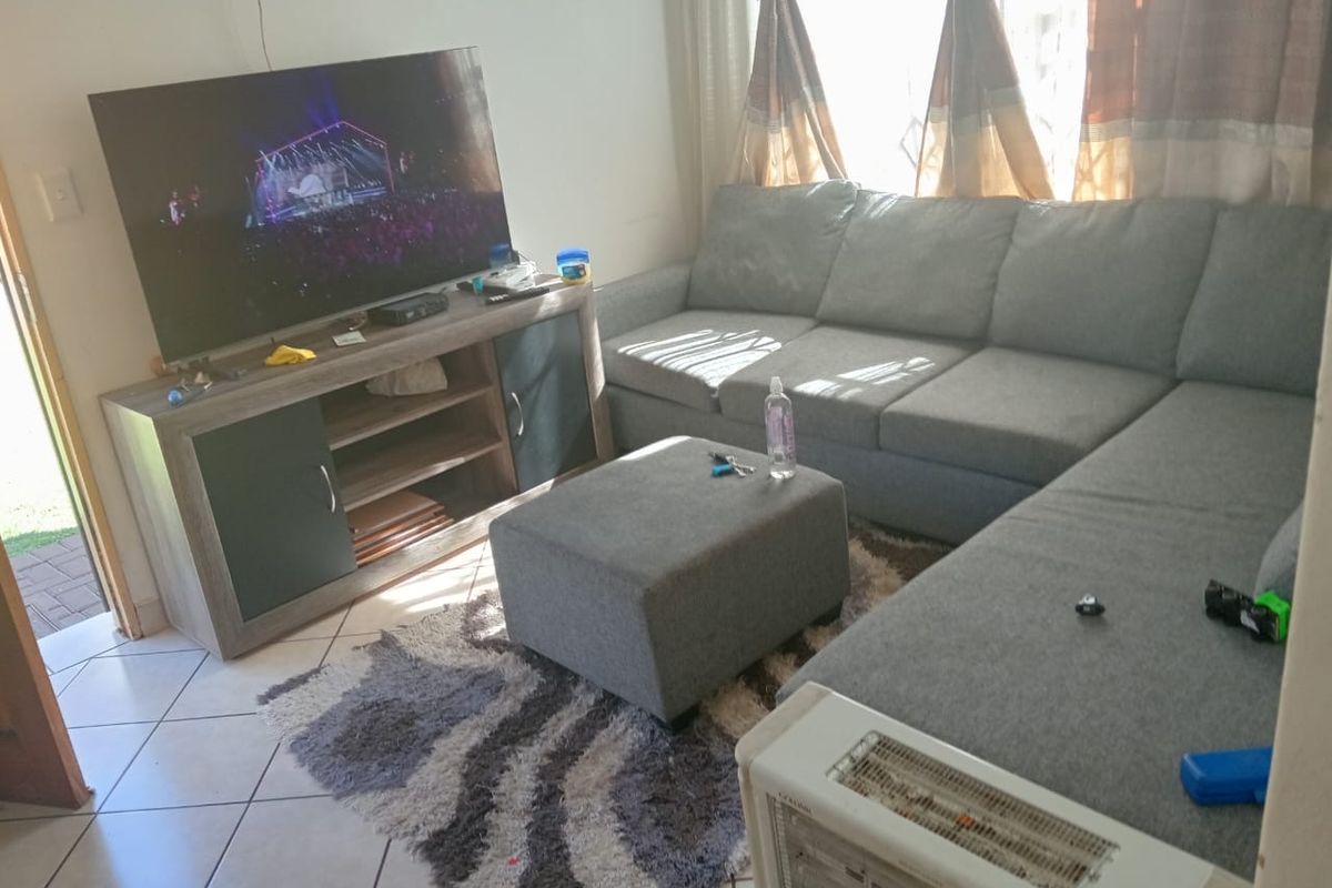 A comfortable living room featuring tiled flooring and direct access to the exterior via a sliding door.