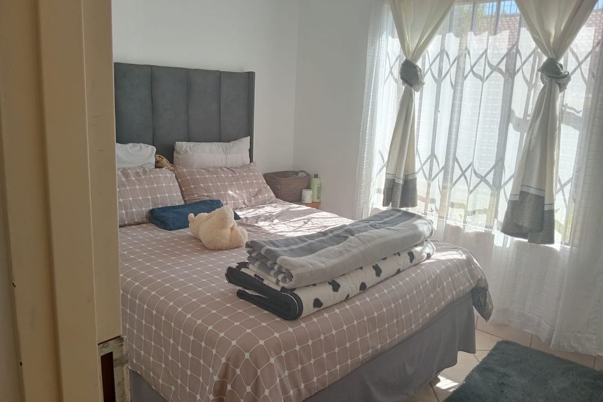 A bedroom featuring tiled flooring and a security gate on the window, providing a functional and secure living space.