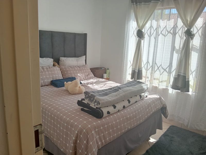 A bedroom featuring tiled flooring and a security gate on the window, providing a functional and secure living space.