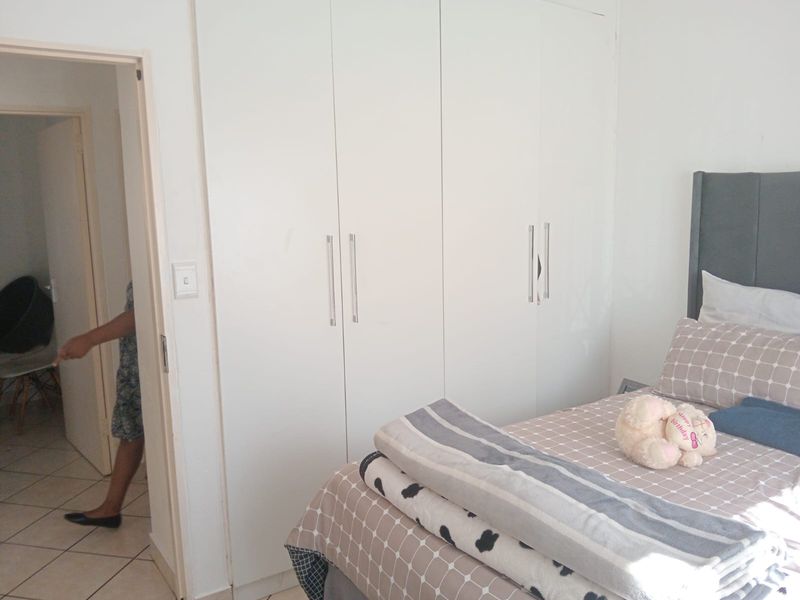A bedroom featuring built-in cupboards with modern handles and tiled flooring, providing functional storage space.
