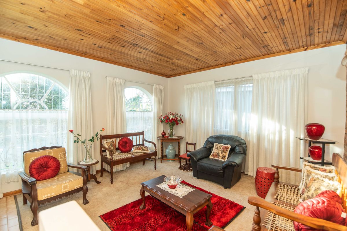 A bright living room featuring a warm timber-clad ceiling and multiple arched windows that provide ample natural light.