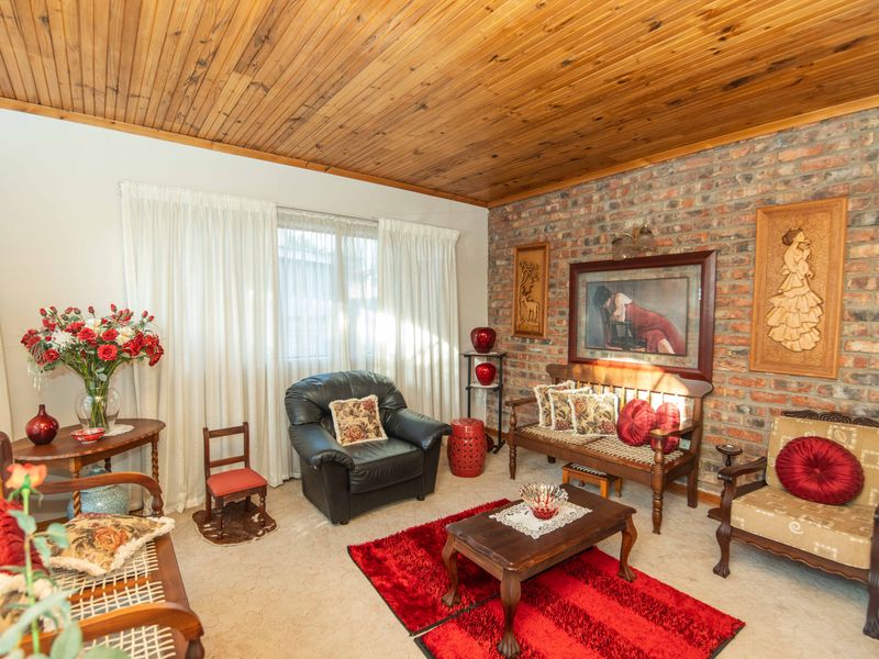 A cozy living room featuring a rustic exposed brick feature wall and a warm timber tongue and groove ceiling.
