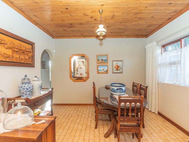 A traditional dining room featuring a warm timber-clad ceiling, ceramic tile flooring, and a classic archway leading to adjacent living spaces.
