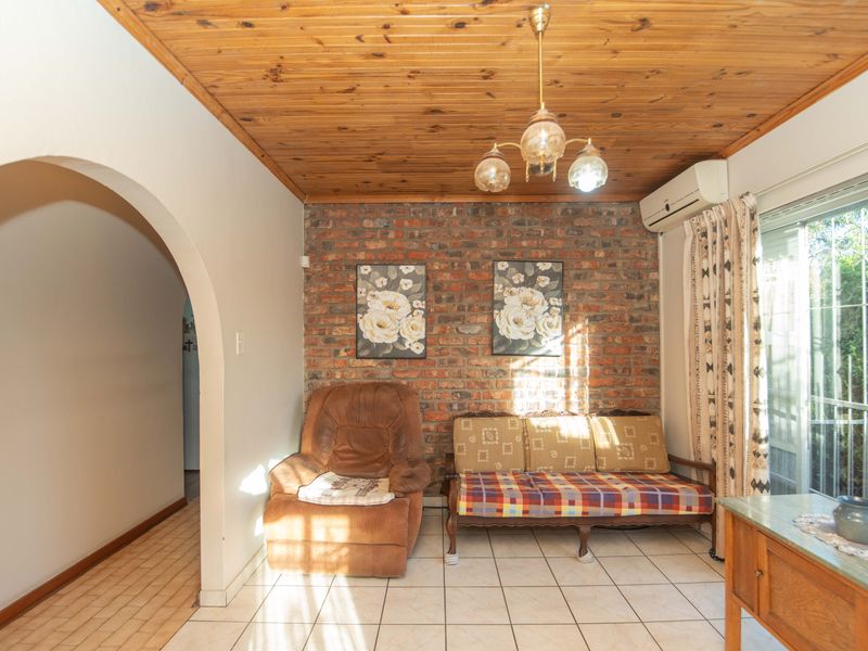 Living room featuring an exposed brick wall, timber ceiling, ceramic tiled flooring, and direct access to the exterior via a sliding glass door.