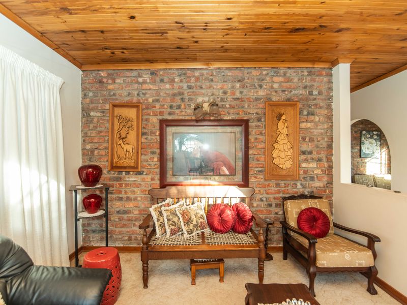 A cozy living room featuring a prominent exposed brick feature wall and a warm timber tongue and groove ceiling.