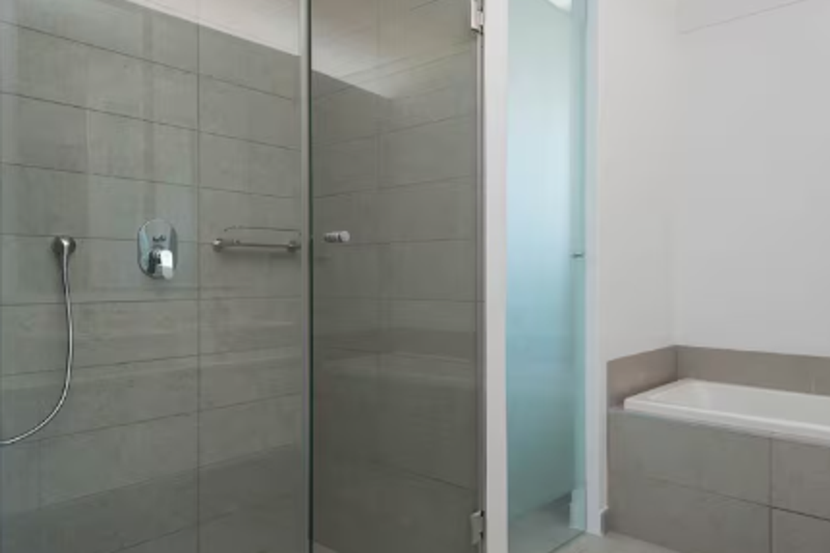 Modern bathroom featuring a walk-in shower with glass screen, built-in bathtub, and contemporary grey wall tiling.