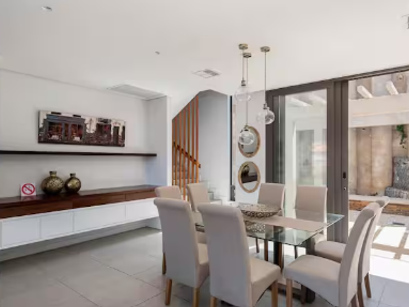 Modern dining area featuring tiled floors, built-in cabinetry, and large sliding glass doors providing seamless access to the outdoor patio area.