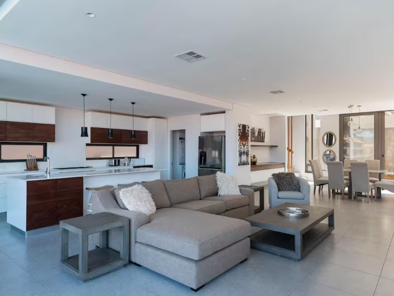 Spacious open-plan living area featuring a modern kitchen with dark wood cabinetry, a central island, and seamless flow to the dining and lounge spaces.