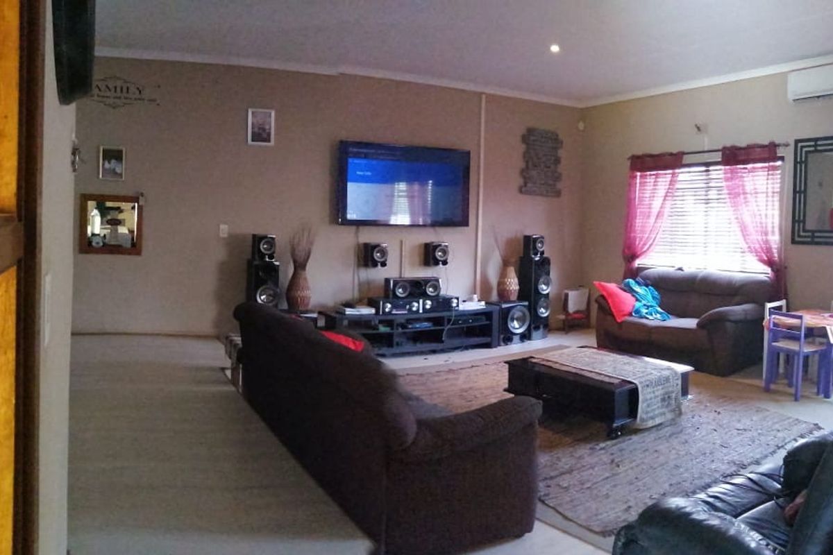 Spacious living room featuring a split-system air conditioner, recessed lighting, and large windows with venetian blinds.
