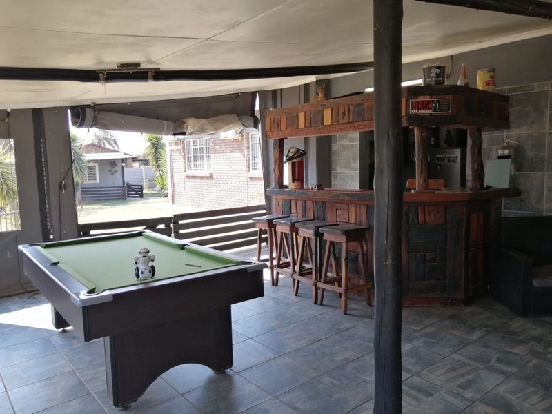 Covered outdoor entertainment area featuring a built-in timber bar, tiled flooring, and space for recreational activities.