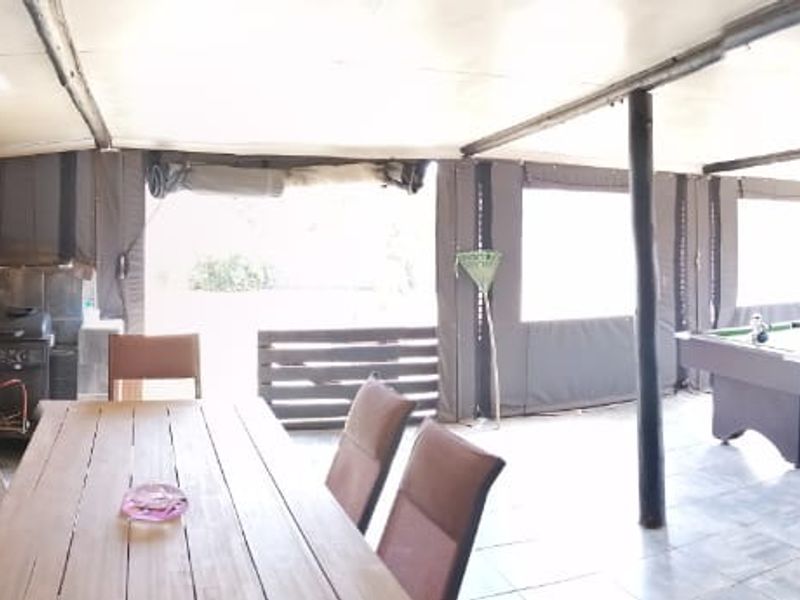 Spacious covered patio featuring a built-in braai, integrated bar area, and tiled flooring, ideal for outdoor entertaining and social gatherings.