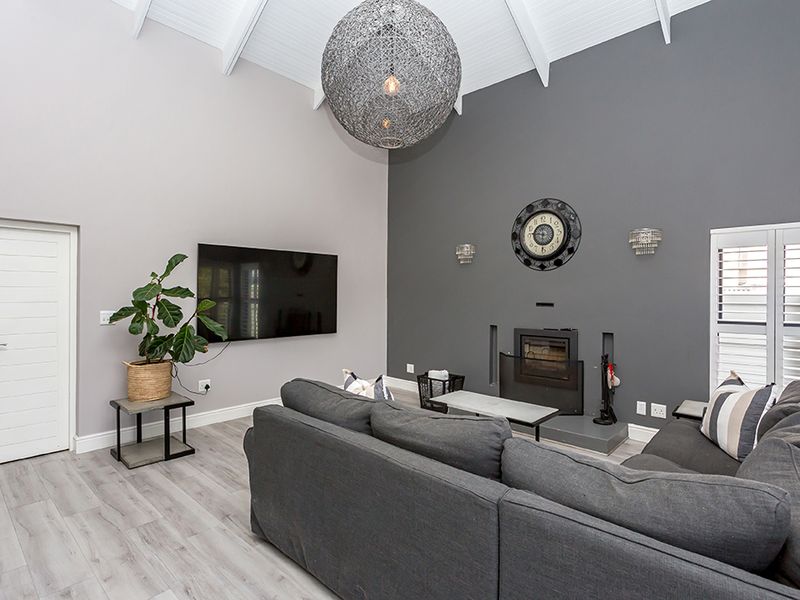 Spacious living room featuring a high vaulted ceiling, modern laminate flooring, and a built-in fireplace set against a feature wall.