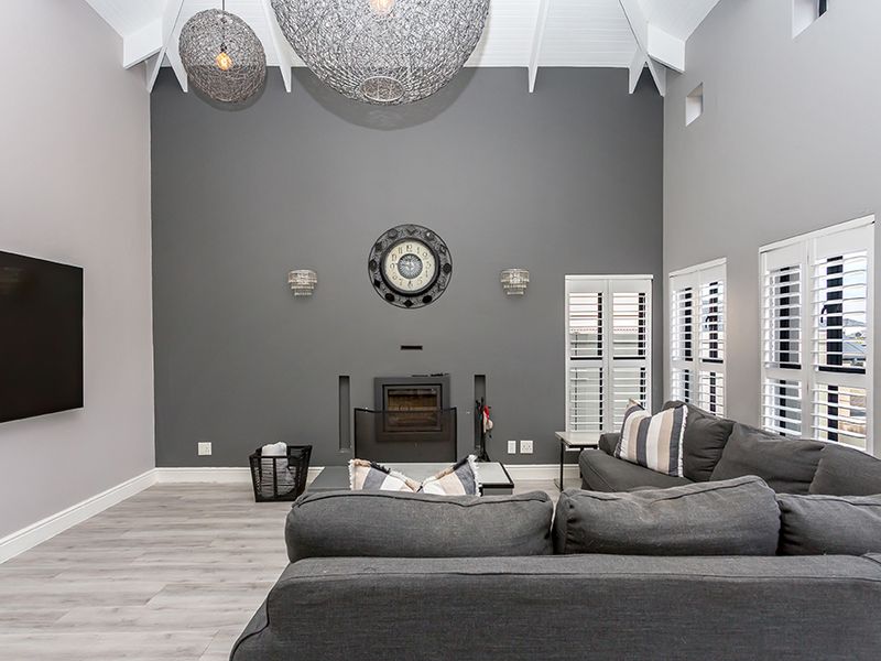 Spacious living room featuring a high vaulted ceiling with exposed rafters, a built-in fireplace, and modern plantation shutters.