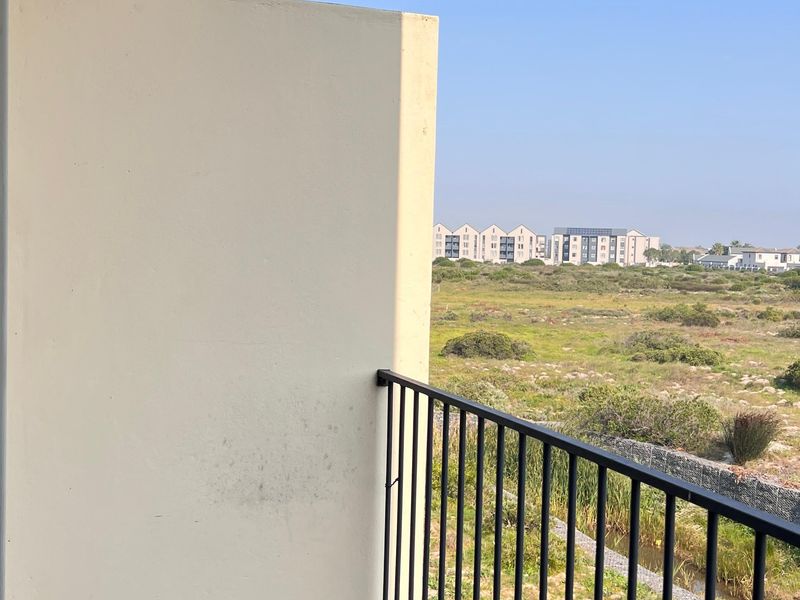 A private balcony featuring tiled flooring and a metal balustrade, offering an open view of the surrounding landscape.