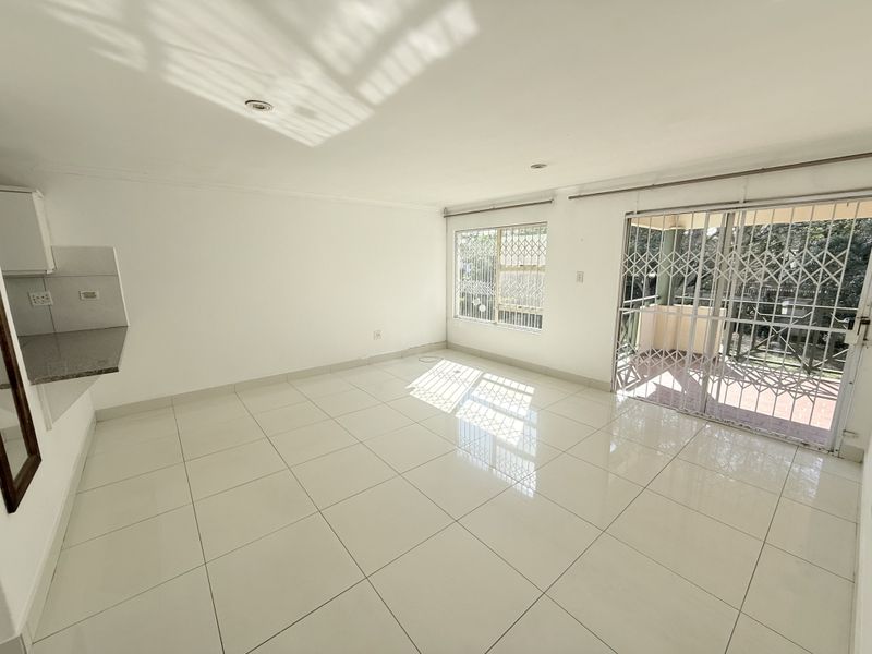 Bright and spacious open-plan living area featuring polished tile flooring, security gates, and direct access to a private balcony.