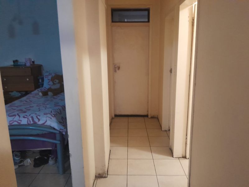 A functional hallway featuring tiled flooring and a transom window, providing access to adjacent rooms within the apartment.