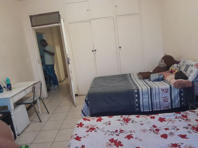 A bedroom featuring built-in cupboards and tiled flooring, requiring cosmetic updates to improve the overall aesthetic and condition of the space.