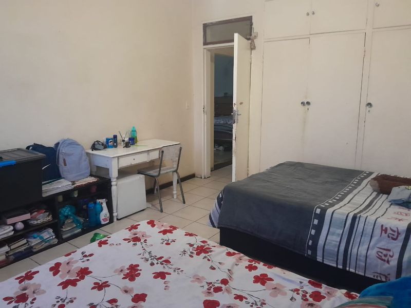 A bedroom featuring built-in cupboards and tiled flooring, offering a functional space with potential for cosmetic updates to improve the overall aesthetic.
