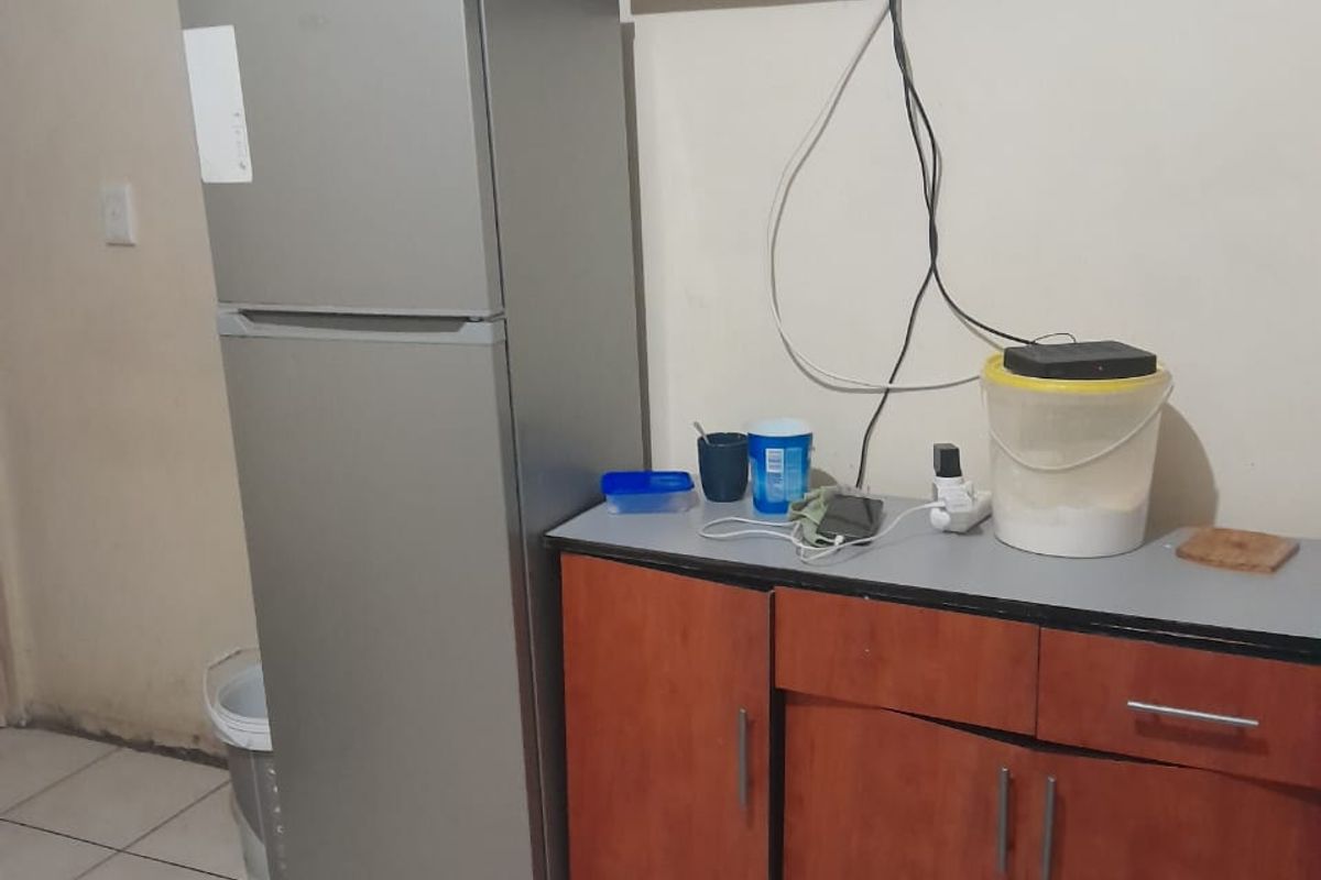 A small kitchen area featuring tiled flooring and basic base cabinetry with a laminate countertop, currently showing signs of wear and dated finishes.